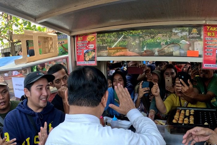 Menteri Pertahanan Prabowo Subianto menunggu giliran jajan takoyaki di tengah suasana heboh masyarakat menyambut kedatangannya. (Dok. Tim Media Prabowo Subianto)